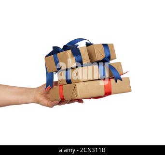 hand holds a stack of wrapped gifts in brown craft paper with tied silk bows Stock Photo