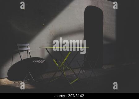 Empty table and chair bathed in light and shadows Stock Photo