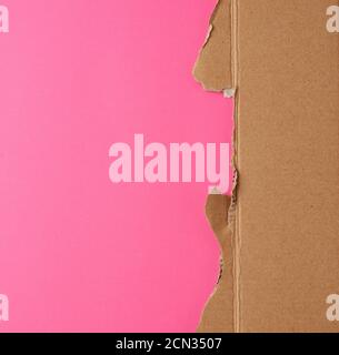 torn edges of corrugated brown cardboard paper on a pink background Stock Photo