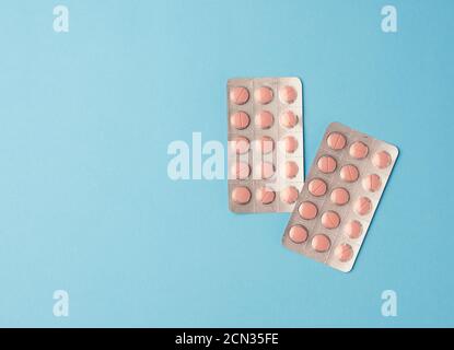 round pink pills in blister packs on a blue background Stock Photo