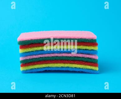 stack of new multi-colored kitchen sponges for washing dishes on a blue background Stock Photo