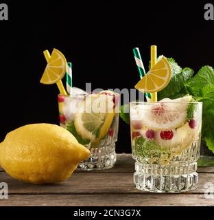 transparent glass with lemonade and pieces of ice, red berries, a refreshing summer drink Stock Photo