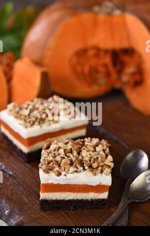 Pumpkin pie - light, creamy dessert with cheese cream and pumpkin layers topped with chopped nuts Stock Photo