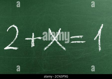 Tricky math equation on the green School blackboard. Handwriting simple mathematical equations. Education and learning Stock Photo