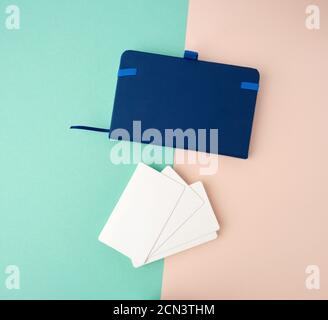 stack of rectangular white blank business cards and blue notebook on a green beige background Stock Photo