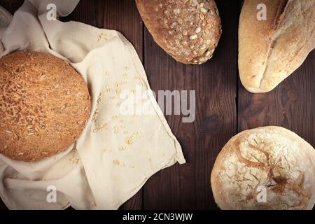 baked various breads on a beige kitchen towel, wooden background Stock Photo
