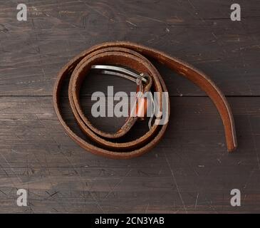 brown leather men's belt with metal buckle on a wooden background Stock Photo