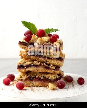 stack of square slices of baked crumble pie with blue plum on a white wooden board Stock Photo