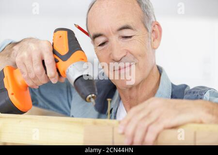 senior carpenter using cordless screwdriver on wood Stock Photo