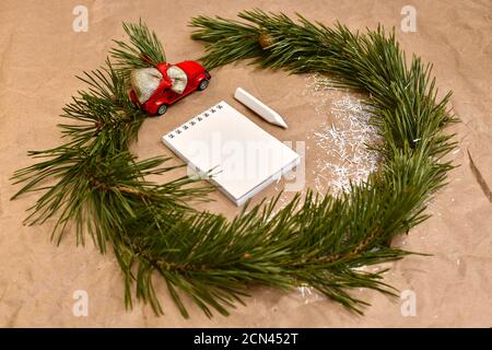 A wreath of pine branches with a red typewriter with a bag of gifts, around a notebook with a pencil in the center.  Stock Photo