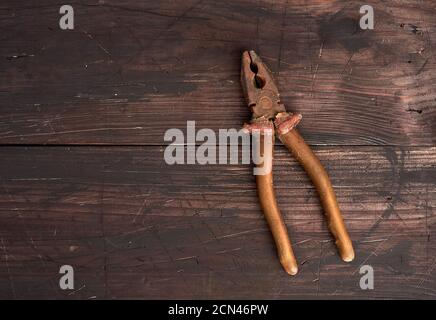 old vintage pliers on a brown wooden background Stock Photo