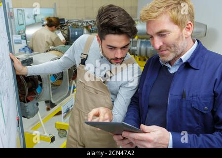 two men working in workshop looking at tablet Stock Photo