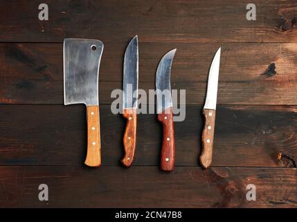 set of different kitchen knives with wooden handles on a brown background from boards Stock Photo