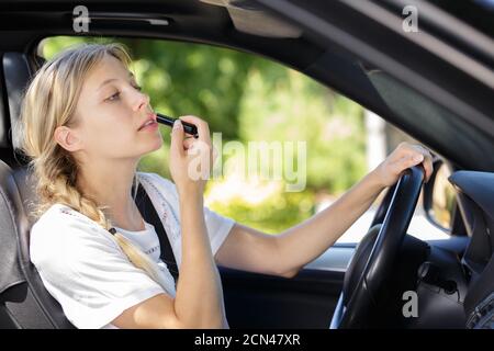 a woman is doing makeup while in the car Stock Photo