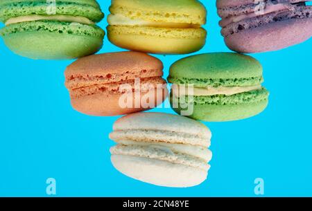 stack of multi-colored round baked macarons cakes on a blue background Stock Photo