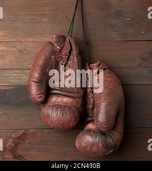 pair of brown leather boxing gloves hang on a wooden wall Stock Photo