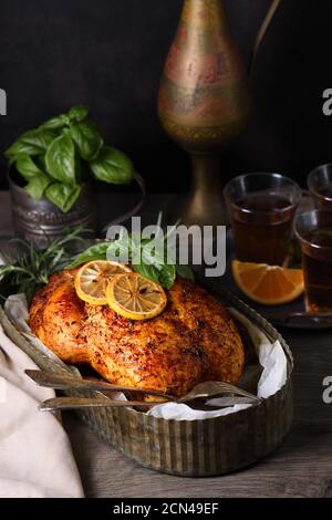 Baked whole chicken in spices with crispy appetizing fried crust in a tray, dark moody Stock Photo