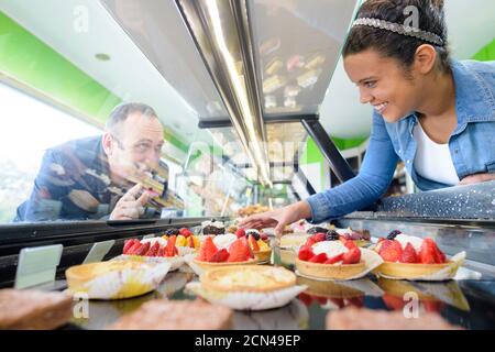 smiling female staff offering fresh pastry in sweet-shop Stock Photo