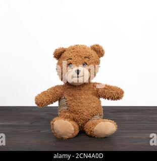 brown teddy bear sits on a brown wooden table Stock Photo