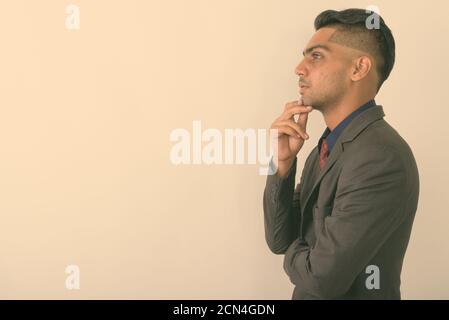 Young Indian businessman wearing suit against white background Stock Photo