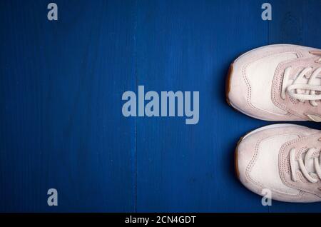 pair of leather pink sneakers on a blue wooden background Stock Photo