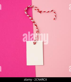 white paper rectangular tag on a rope on a colored background Stock Photo