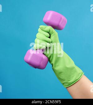 female hand holds a plastic pink dumbbell on a blue background Stock Photo