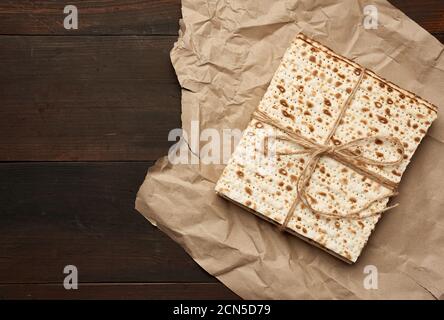 bandaged stack of baked square matzoh on brown paper, top view Stock Photo