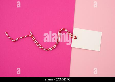 white paper rectangular tag on a rope on a colored background, flat lay Stock Photo