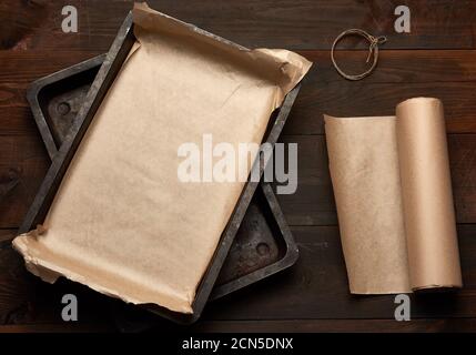 empty rectangular metal pan covered with brown parchment paper and paper rolls Stock Photo