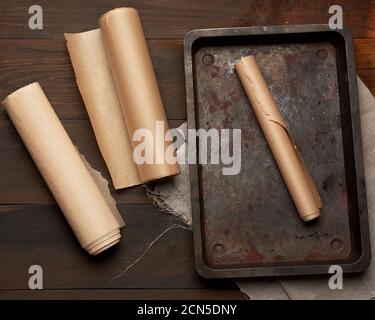 empty rectangular metal pan and rolls of brown parchment paper Stock Photo