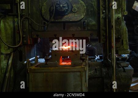 close-up picture of fresh forged hot steel workpieces after press forming in dirty dark factory Stock Photo