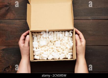 two female hands hold an empty open box of brown cardboard Stock Photo