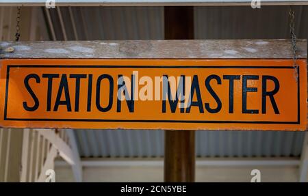 Station Master sign hanging by a chain from a timber board