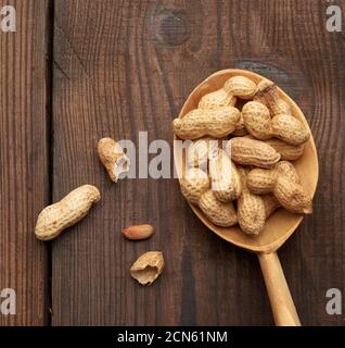 unpeeled peanuts in a wooden spoon on the table, tasty and healthy fruit Stock Photo