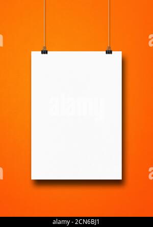 White poster hanging on an orange wall with clips Stock Photo