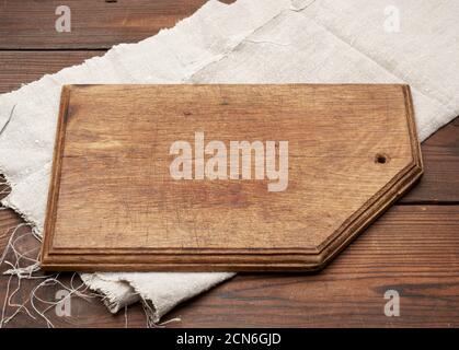 old brown rectangular wooden kitchen cutting board and gray linen napkin on the table Stock Photo