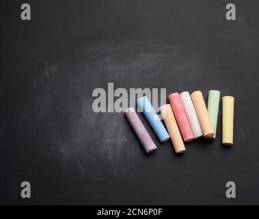 multicolored chalk on lie on empty black chalk board Stock Photo
