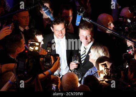 Guido Westerwelle (centre R), leader of the pro-business Free Democratic Party (FDP) and his partner Michael Mronz (centre L) celebrate at the FDP venue after the German general election (Bundestagswahl) in Berlin September 27, 2009. German voters gave Chancellor Angela Merkel a second term in an election on Sunday and a mandate to form a new government with the business-friendly Free Democrats (FDP) that is expected to cut taxes to boost growth.   REUTERS/Arnd Wiegmann  (GERMANY POLITICS ELECTIONS)