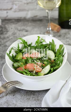 Vegetable salad from arugula, avocado and cucumber pieces with the addition of tender salted salmon, Stock Photo