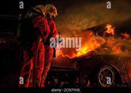 Firefighters spraying down fire flame from car accident Stock Photo