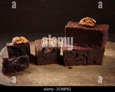 stack of baked pieces of brownie chocolate cake with nuts on a wooden board Stock Photo