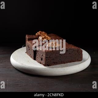 stack of baked pieces of brownie chocolate cake with nuts on a wooden board Stock Photo