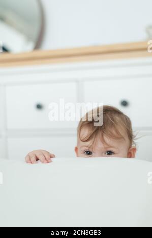 Little girl looking over bed Stock Photo