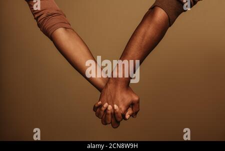 Cropped shot of couple holding hand interlocking fingers. Two people holding hand standing side by side. Stock Photo