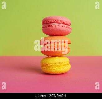 stack of baked macarons on pink green background, delicious dessert made from almond flour Stock Photo