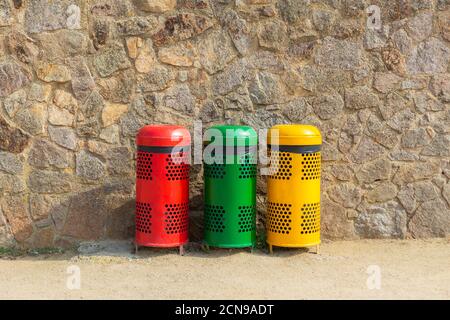 Three multicolored recycle bins for waste near the wall Stock Photo