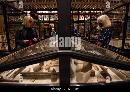 Visitors wearing PPE during preview opening day of the Pitt Rivers Museum, in Oxford. The Museum displays archaeological and ethnographic objects from all parts of the world, which visitors are now able to view once more after the museum was closed due to the coronavirus pandemic. Stock Photo