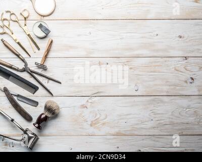 Classic grooming and hairdressing tools on wooden background. Top view on barbershop instruments  laying on white wooden table. Stock Photo