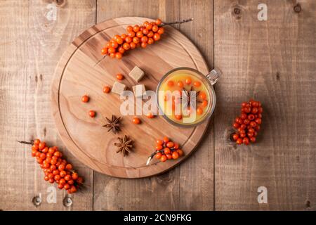 Hot beverage of sea-buckthorn berries in glass cup on wooden background. Rustic style. Top view Stock Photo